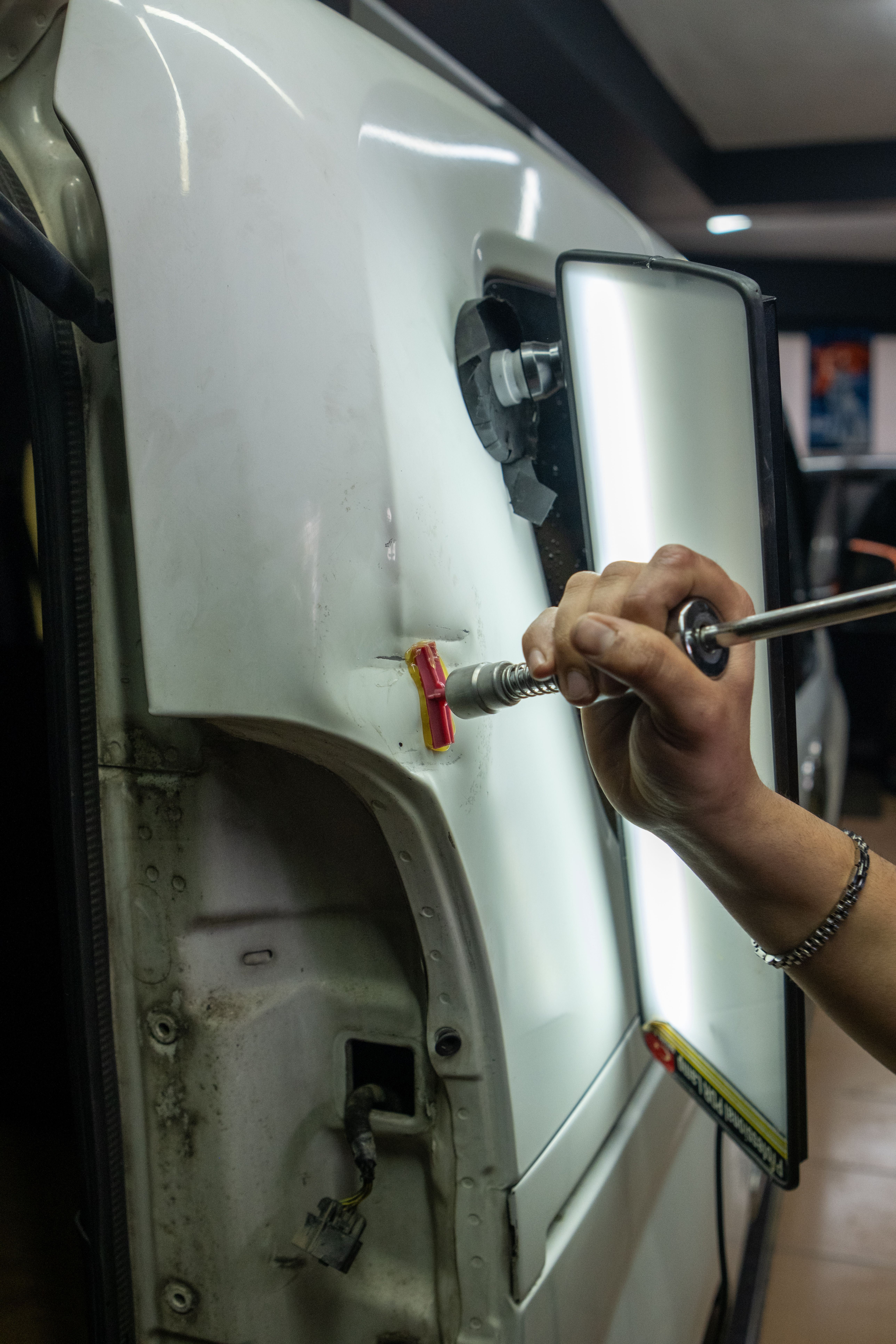 Auto body technician repairing collision damage on a vehicle in a body shop