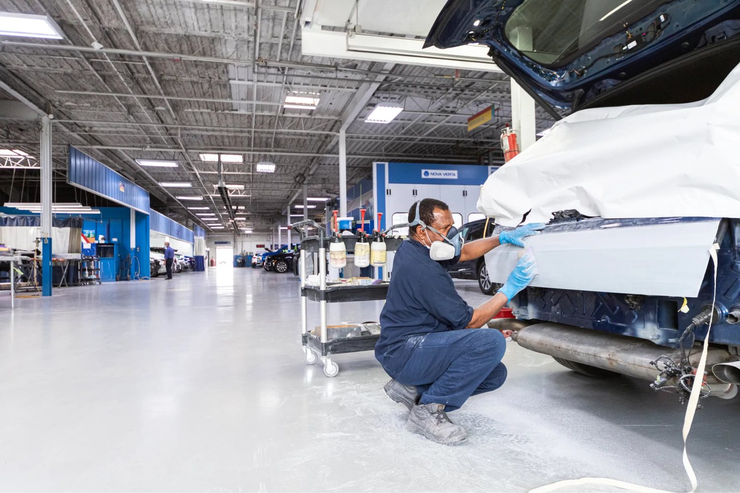 Auto body technician repairing and refinishing a vehicle bumper