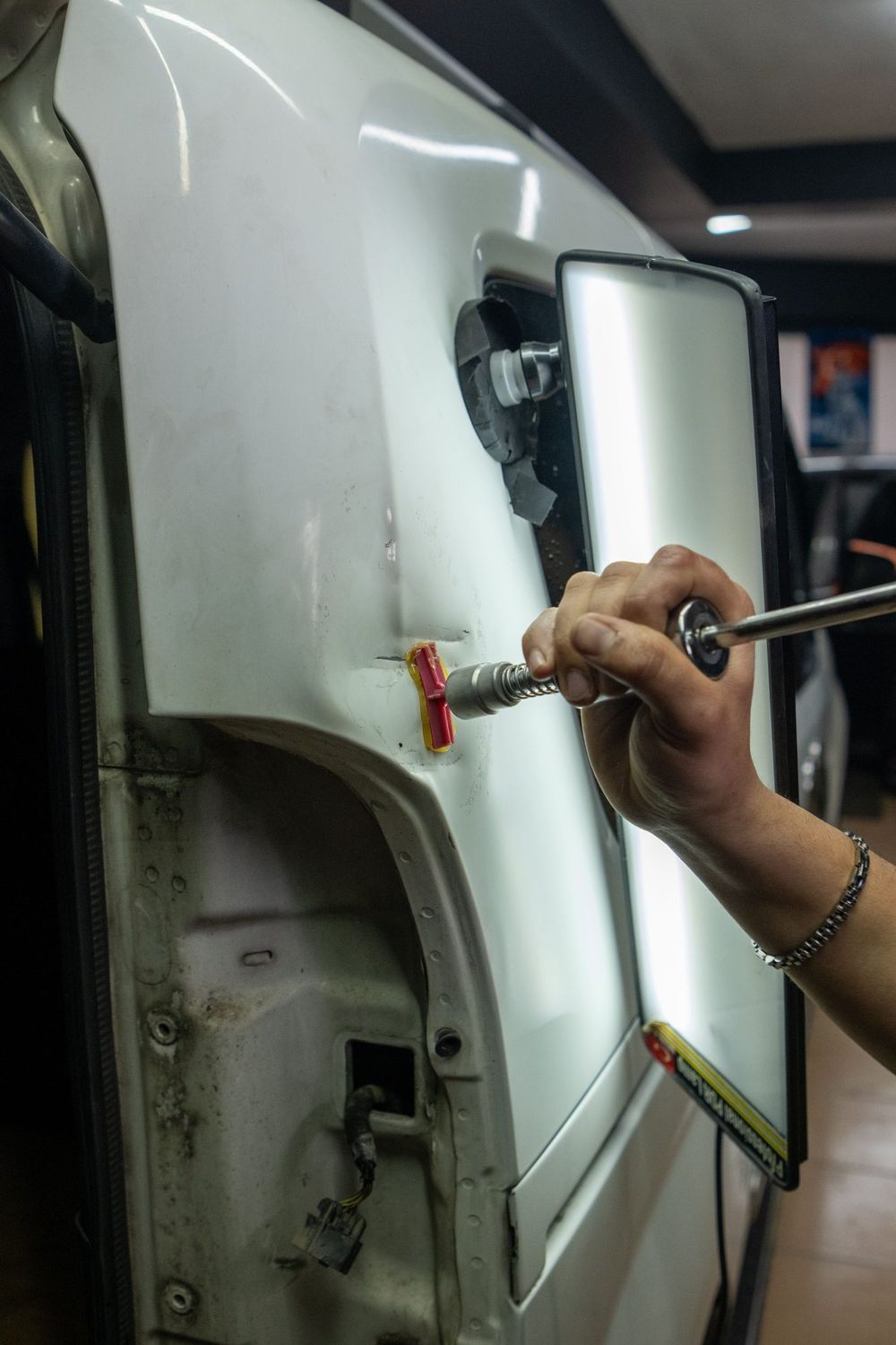 Auto body technician repairing collision damage on a vehicle in a body shop